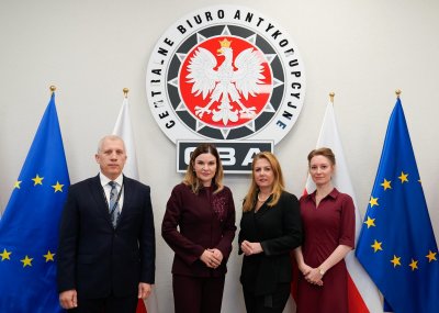 Cztery osoby stojące na tle logo CBA.