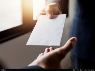 Mężczyzna przekazuje kopertę innemu mężczyźnie.