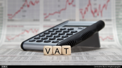 Kalkulator, przed nim klocki z napisem VAT, w tle dokumentacja.