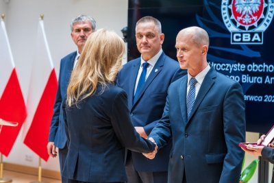 Gen. bryg. Andrzej Kowalski gratuluje elegancko ubranej kobiecie.