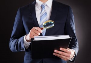A person holding a document and a magnifying glass