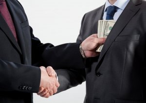People shaking hands, one person passing a bundle of banknotes
