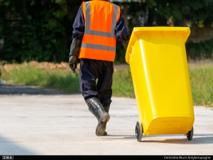 a person pulling a garbage can