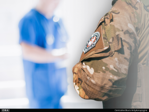 A CBA officer in a uniform, blurred figure of a doctor in the background