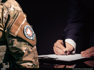 close-up of a uniform, with a signature on a document in the background