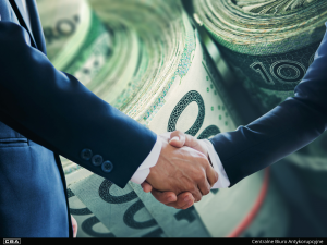 Two people shaking hands, money in the background