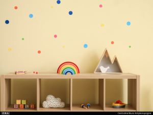 A cupboard with children's toys on it, polka dot wallpaper.