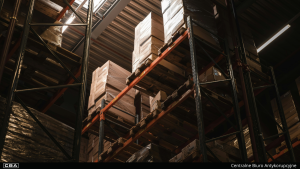 Interior of a high-bay warehouse with metal racks filled with pallets.