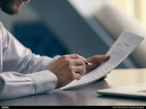 Close-up of a person sitting at a desk using a laptop.